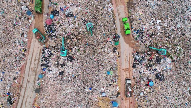 Aerial view from a drone flying over a large pile of garbage, Trash trucks dump waste polluting products. environmental pollution concept. Timelapse. 4K UHD