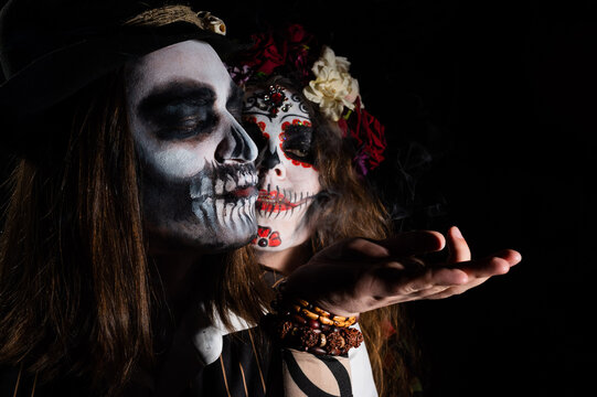 Woman in santa muerte costume and man in skeleton bodypainting for halloween.