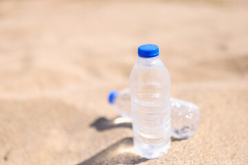 Cold drinking water in transparent bottles on sandy beach sea