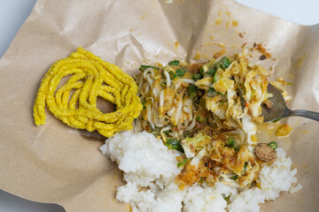 Karedok is ready to eat. It is served on a white plate with brown paper as a base. Karedok is a...
