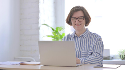 Senior Woman Smiling at Camera while using Laptop