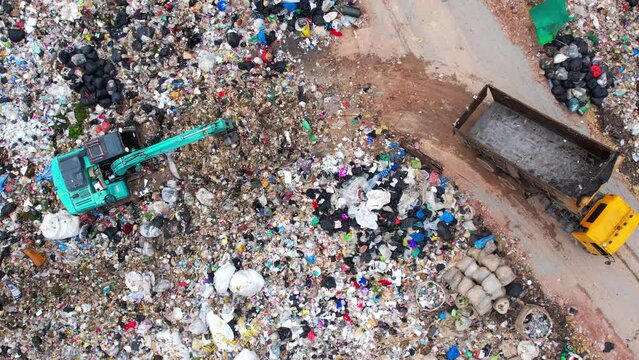 Aerial view from a drone flying over a large pile of garbage, Trash trucks dump waste polluting products. environmental pollution concept. 4K UHD
