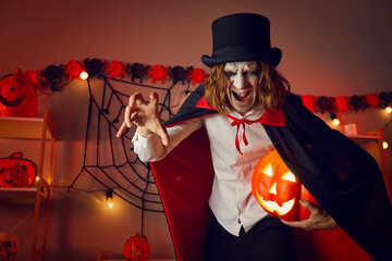 Adult man dressed up in costume of spooky vampire at indoor Halloween party. Portrait of crazy evil...