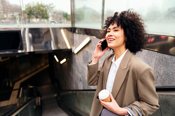smiling business woman talking by phone on the escalator of the subway station, concept of urban lifestyle and public transport, copy space for text