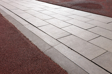 The space around the concrete track is covered with a rubber crumb sports surface. Angle view. Selective focus.