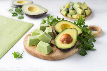 Methods for freezing avocados - in the form of puree in portions, puree in a thin layer, pieces and halves on a light blue background, decorated with parsley. Cooking homemade preparations