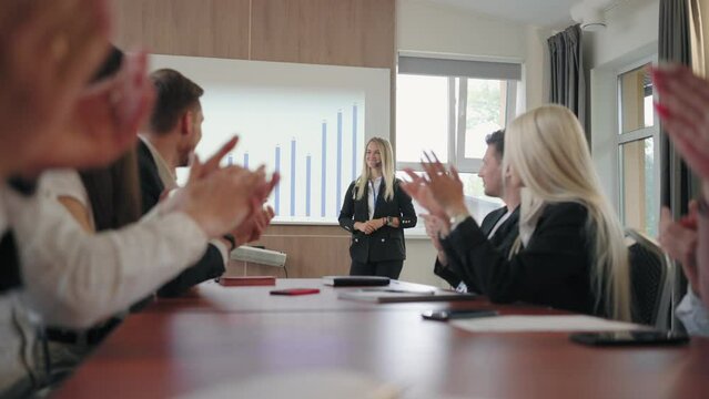 business meeting in big IT company, woman is presenting report with chart on display, colleagues and partners are applauding