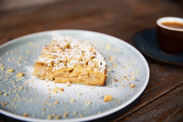 Slice of homemade apple delitious pie on blue big plate with black espresso.