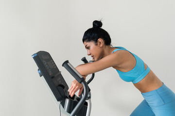 Fototapeta na wymiar Young woman training at the gym using eliptical crosstrainer