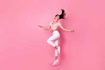 Full length profile photo of hooray millennial brunette lady jump look back wear crop top jeans boots isolated on pink background