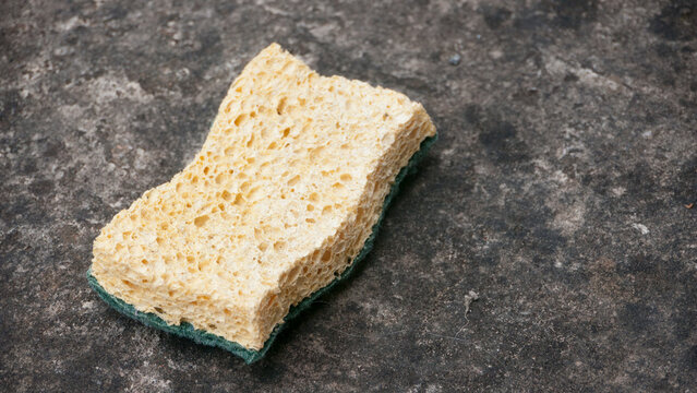 Esponja cuadrada amarilla usada sobre piedra gris