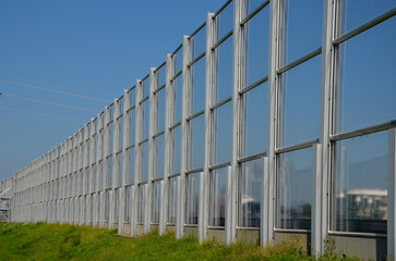 Fototapeta premium soundproof wall of blue glass on a highway bridge embedded in metal beams, on the street. road traffic noise is reduced. safety protection with steel cables against falling on people, tilt, slanted