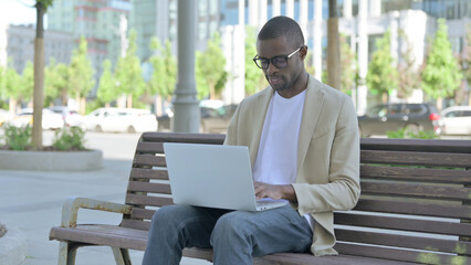 Busy African Man Using Laptop Sitting Outdoor on Bench