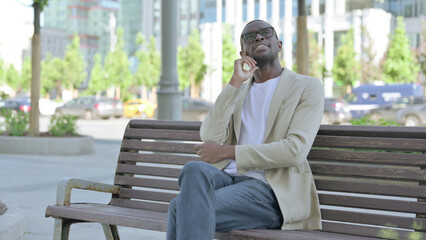 Pensive African Man Thinking while Sitting Outdoor on Bench