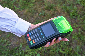 A woman is holding a payment terminal in her hand. Close-up