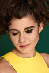 young curly woman with creative make-up in yellow dress