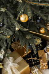 Home interior with decorated Christmas tree in black and gold colors and gifts under it, Merry Christmas and Happy New Year
