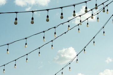 White economy light bulbs hanging in a row. Light bulbs view against the sky.