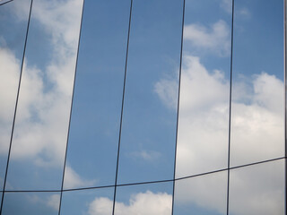 The blue sky and white clouds are reflected on the polished surface of the modern building