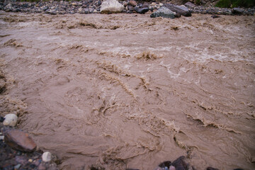 Muddy river water. Spring flood. Dirty muddy water with a whirlpool and white foam close-up.A mountain river or stream raging during a flash flood.
