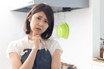 キッチンで悩む女性
