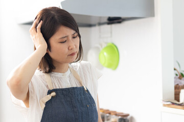 キッチンで頭を抱える女性 © kimi