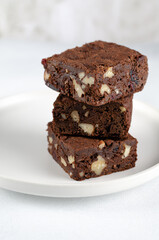 Chocolate homemade brownies with dried cranberries and walnuts on the white  plate
