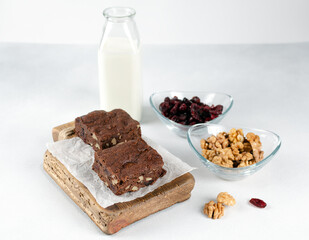 Chocolate homemade brownies with dried cranberries and walnuts on the wooden board with a bottle of milk. Copy space for text