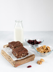 Chocolate homemade brownies with dried cranberries and walnuts on the wooden board with a bottle of milk