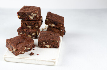 Chocolate homemade brownies with dried cranberries and walnuts on the white wooden board with...