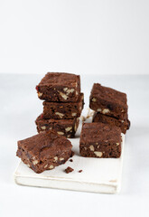Chocolate homemade brownies with dried cranberries and walnuts on the white wooden board with background. Copy space for text