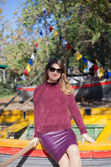 Beautiful woman in sunglasses in burgundy sweater on a background of autumn tree.
