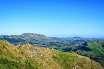 Man on the mountain peak looking over vast green valley and enjoying beautiful summer mountain landscape. A panoramic view of Te Mata Hills iin Hawke's Bay, New Zealand