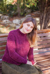 Portrait of beautiful woman in burgundy sweater on a background of autumn tree.	
