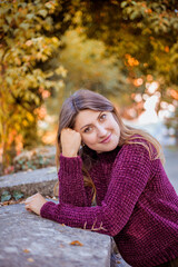 Fototapeta premium Portrait of beautiful woman in burgundy sweater on a background of autumn tree. 