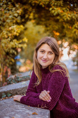Obraz premium Portrait of beautiful woman in burgundy sweater on a background of autumn tree. 