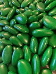Green background with green dragees. Green chocolate coated dragee with almond flavour.