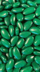Green background with green dragees. Green drage with almond flavour.