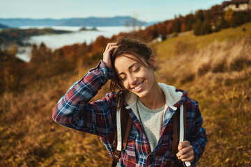 Portrait happy carefree girl enjoying hiking in mountains, standing on slope of hiils with fall...