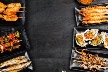 Various barbecue delicacies are placed on the black wood background