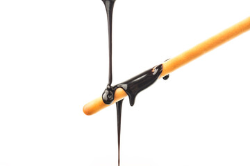 The chocolate sauce flows over the biscuit stick