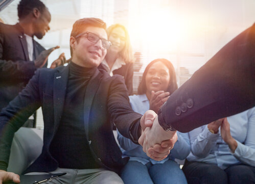 employees congratulating their colleague at a work meeting.