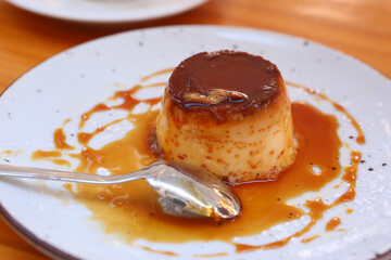  spanish flun pudding dessert close up photo with teaspoon and cup of coffee on the background