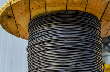 Big wooden spool with black cable in the plant close-up.