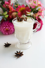 original candle made of natural soy wax in a glass goblet and bouquet of flowers