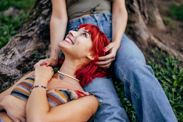 Naklejka premium Close up of a girl laying on her girlfriends lap and looking at the with a smile on her face.