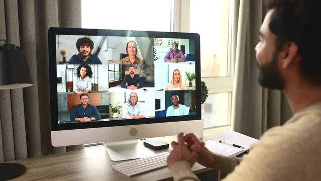 Morning meeting on the distance. Indian mixed-race man using computer app for video connect with group of diverse colleagues. Multiracial guy take a part in educational seminar, involved webinar