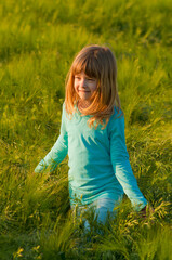 Fototapeta premium Smiling little girl walking in the wheat field on a sunny summer day