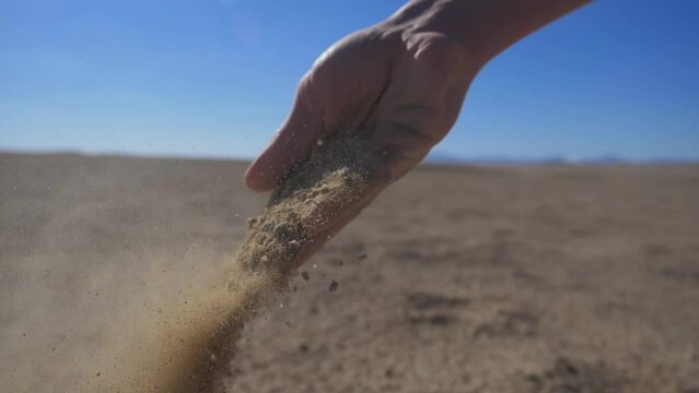 sand slipping through the fingers, male hands close up. desert landscape. beautiful nature video. sunset over the sand dunes in the desert