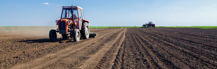 Farmers with tractors sowing on agricultural fields on sunny spring day
